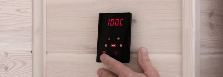 Person bedient ein Bedienpult an einer Wand aus hellem Holz.